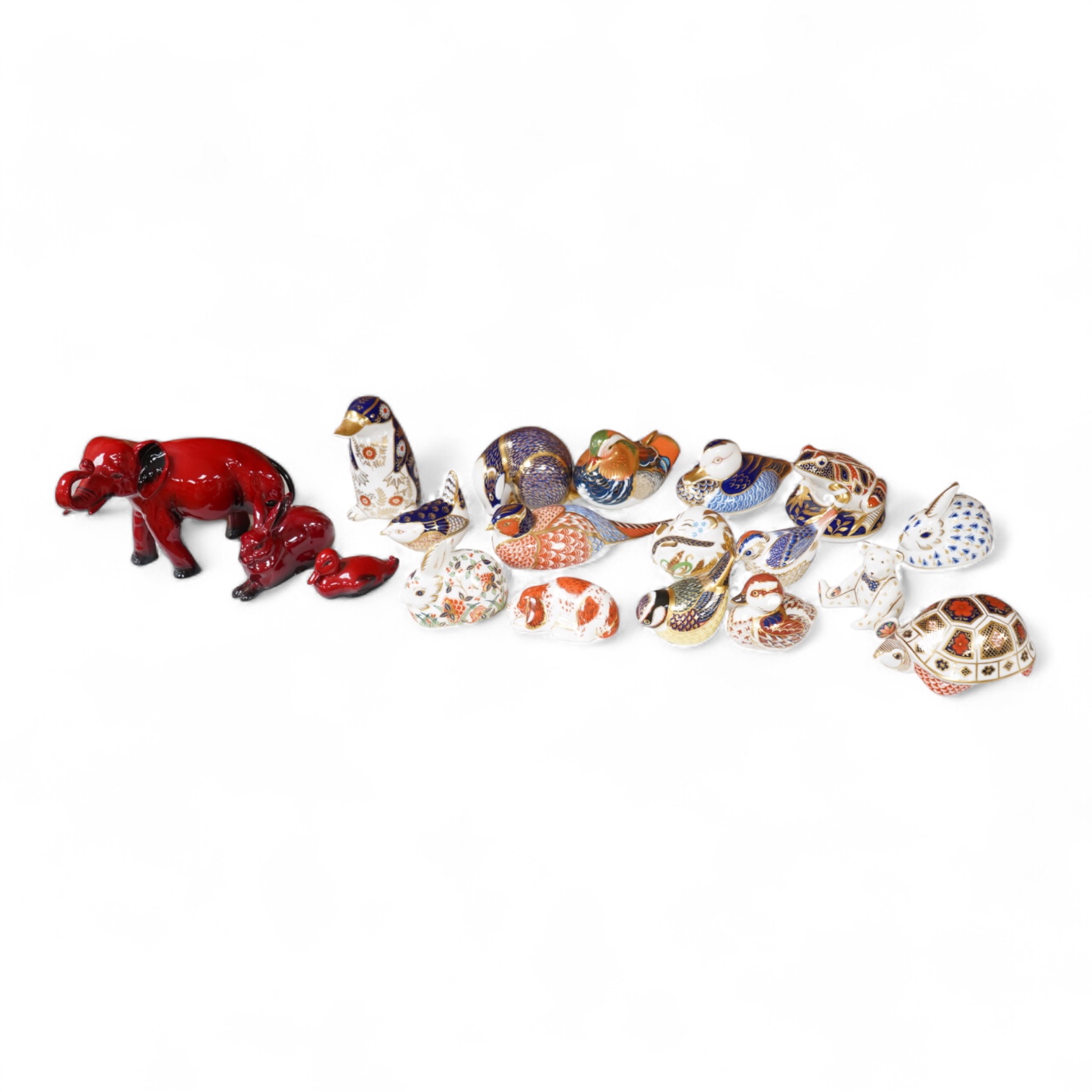 A collection of Royal Crown Derby Imari pattern paperweights, to include penguin and badger, together with three Doulton flambé animals, largest 19cm wide